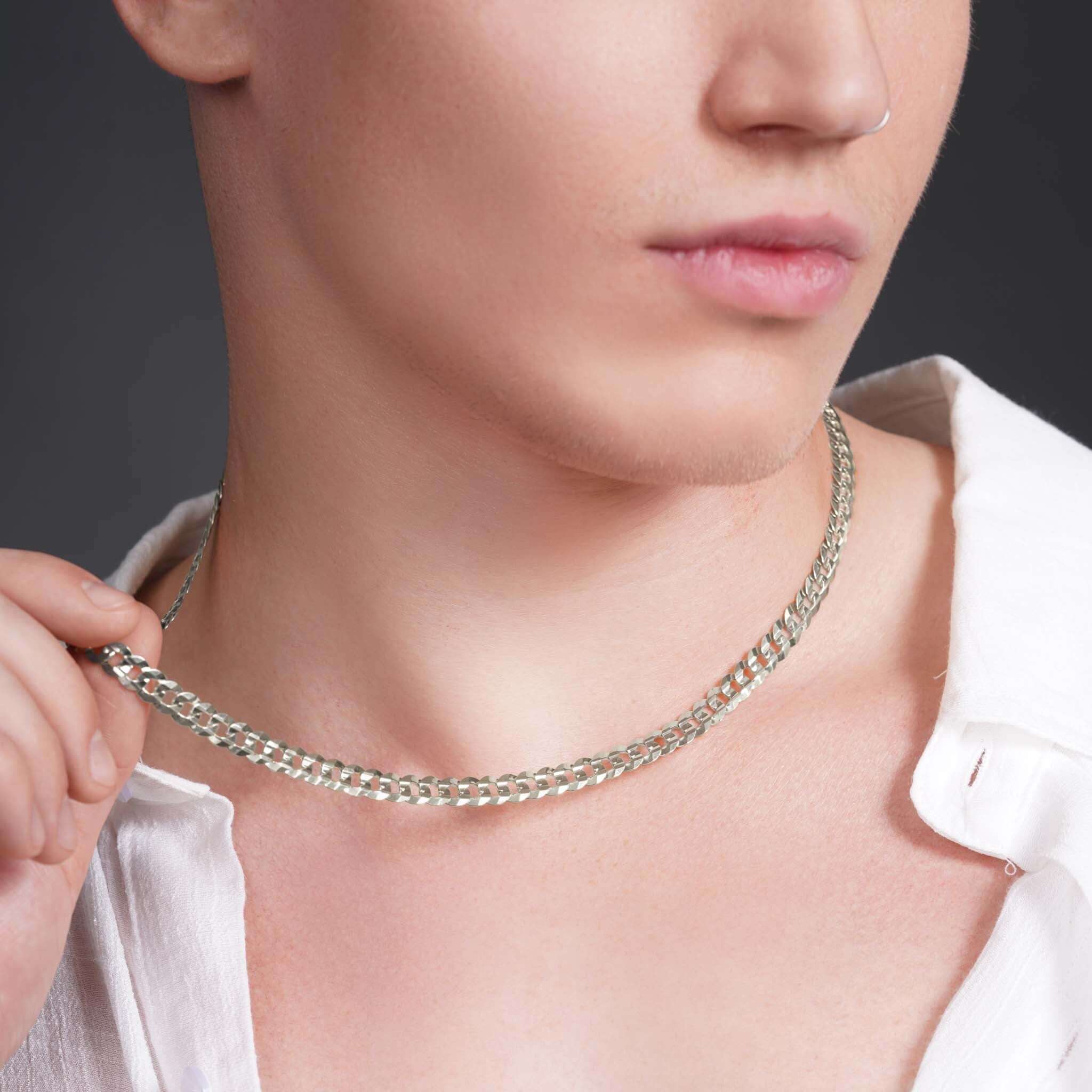 Stylish man showcasing a silver men's solid gold curb chain necklace against a dark background.