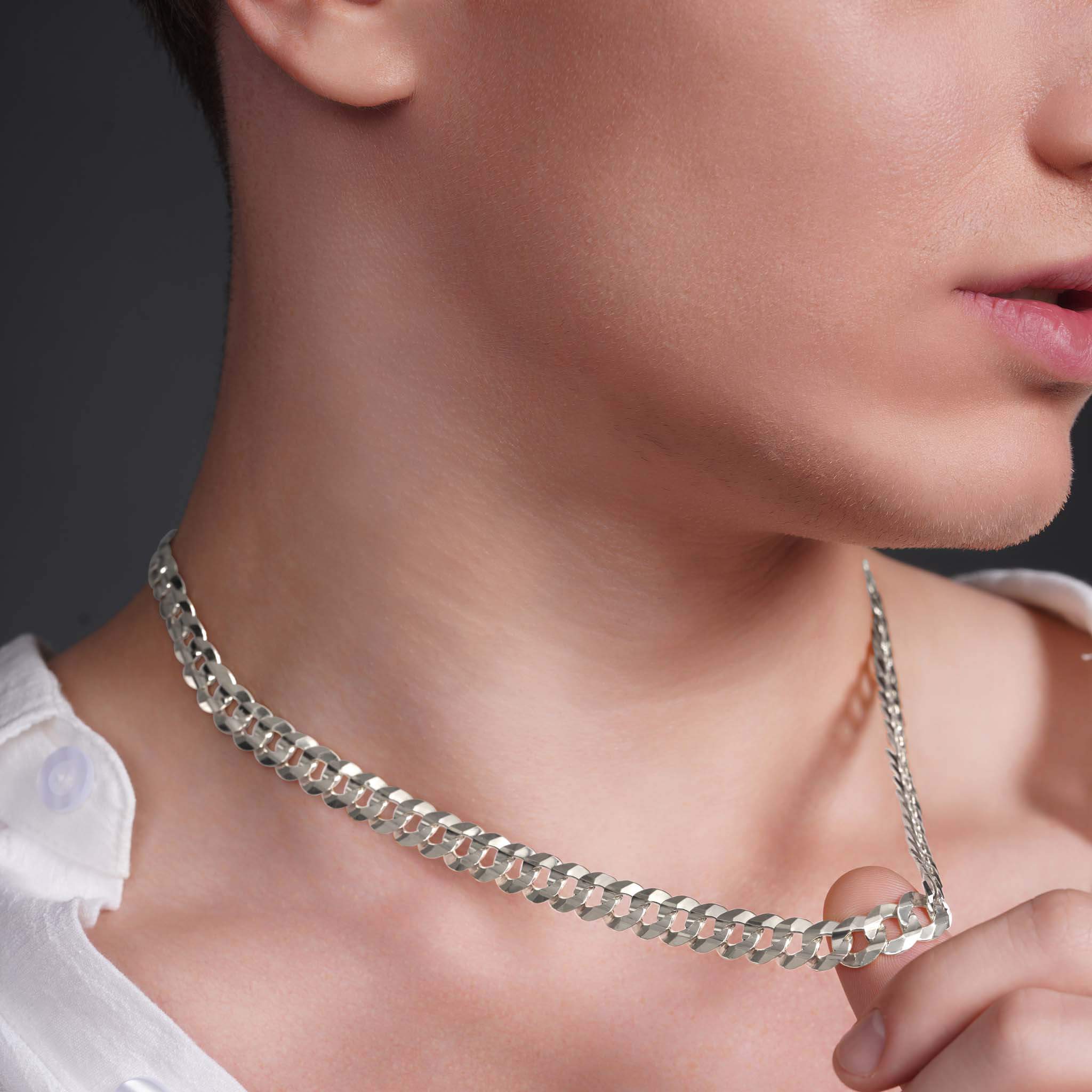 Close-up of a man wearing a sleek solid gold curb chain, highlighting its elegant design and shine.