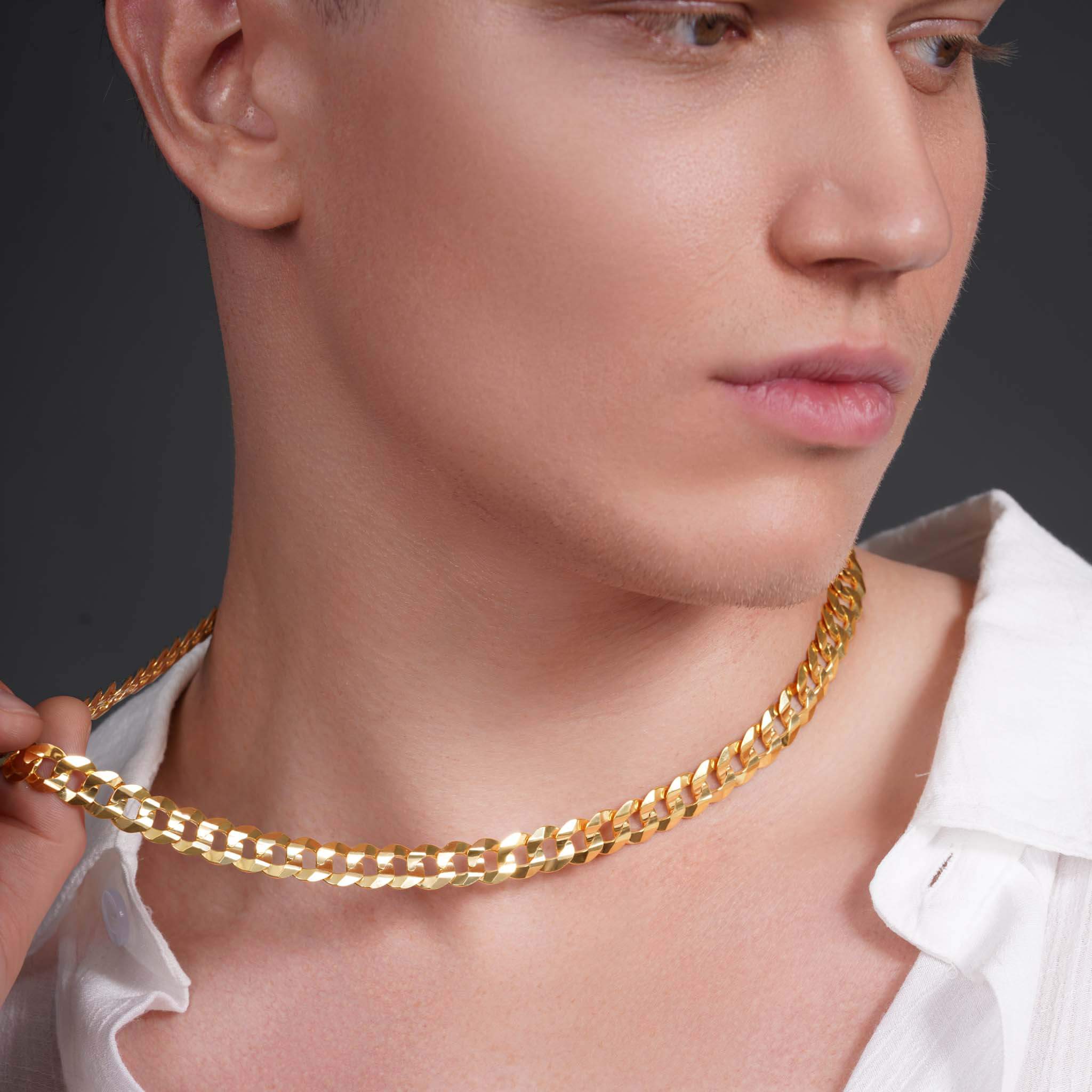 Close-up of a man wearing a men's solid gold curb chain, showcasing its style and shine against his skin.