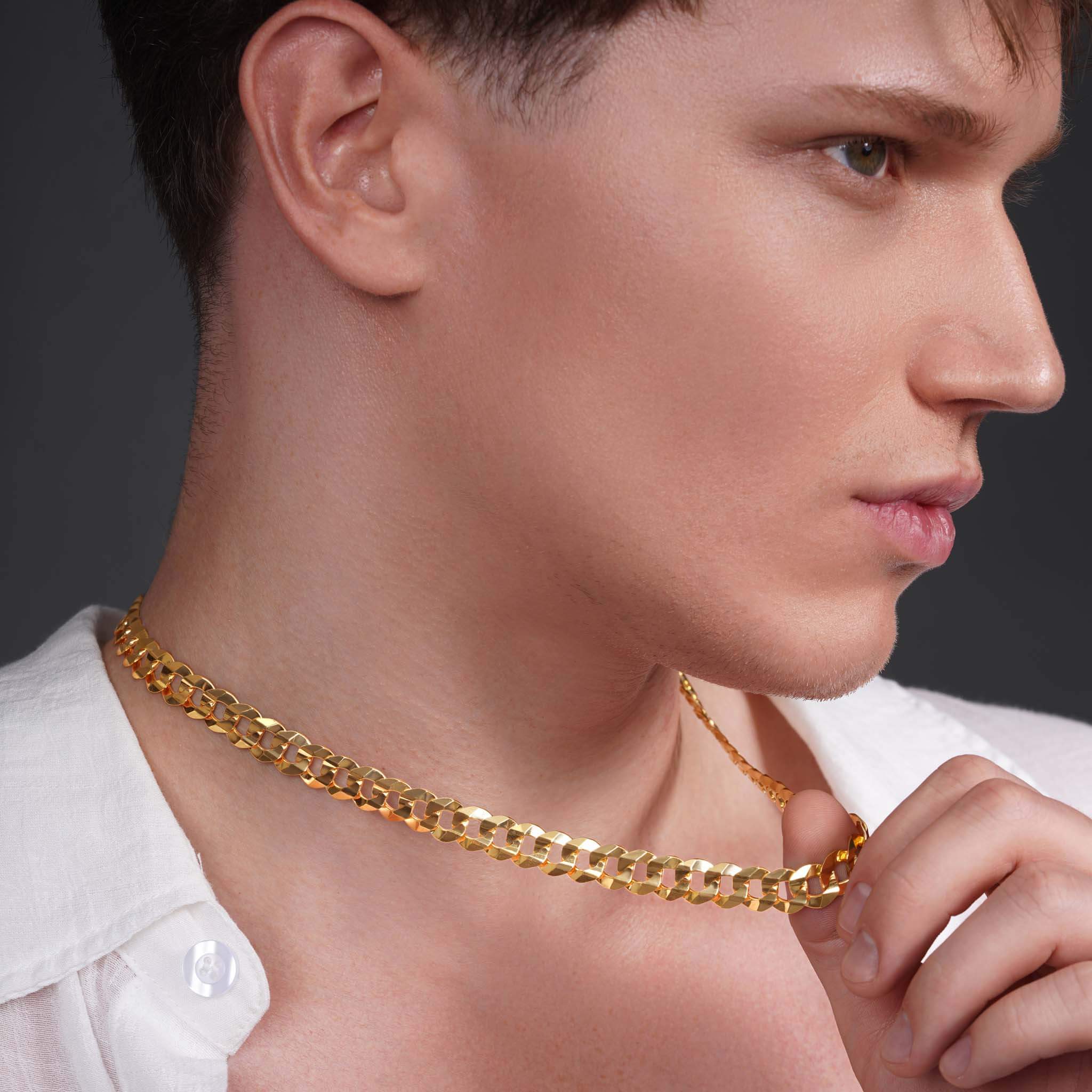Close-up of a man wearing a shiny gold curb chain necklace, showcasing its smooth, interlocking links.