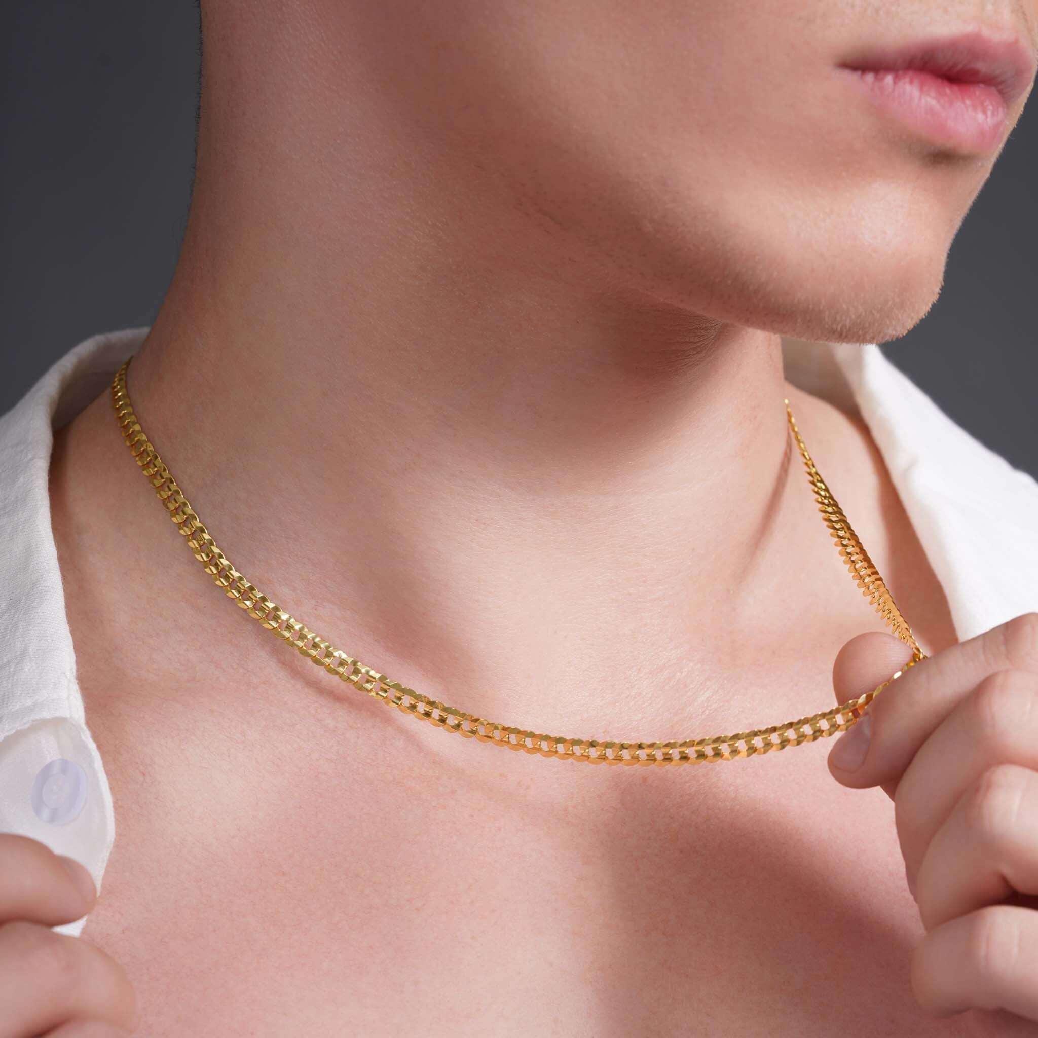 Close-up of a man wearing a Men's Solid Gold Curb Chain, showcasing its elegant design and shine.