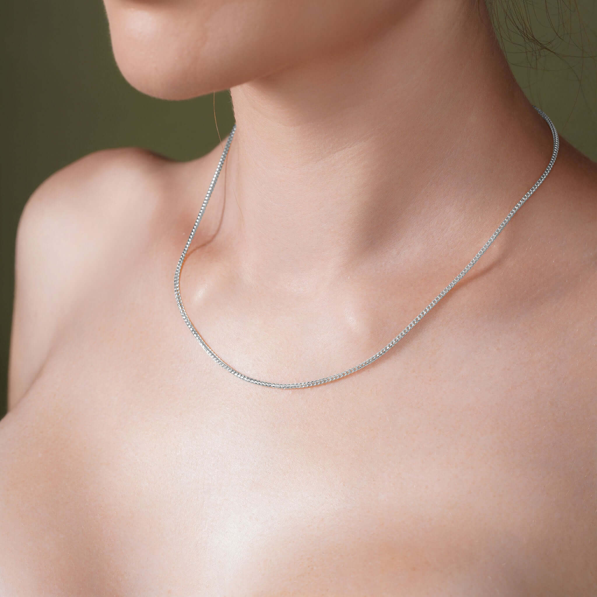 Close-up of a woman wearing a Diamond Cut Franco Chain in silver, showcasing its sparkle and elegance.