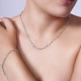 Elegant woman wearing a Figaro Gold Chain and bracelet, showcasing classic style and sophistication in 14k white gold.