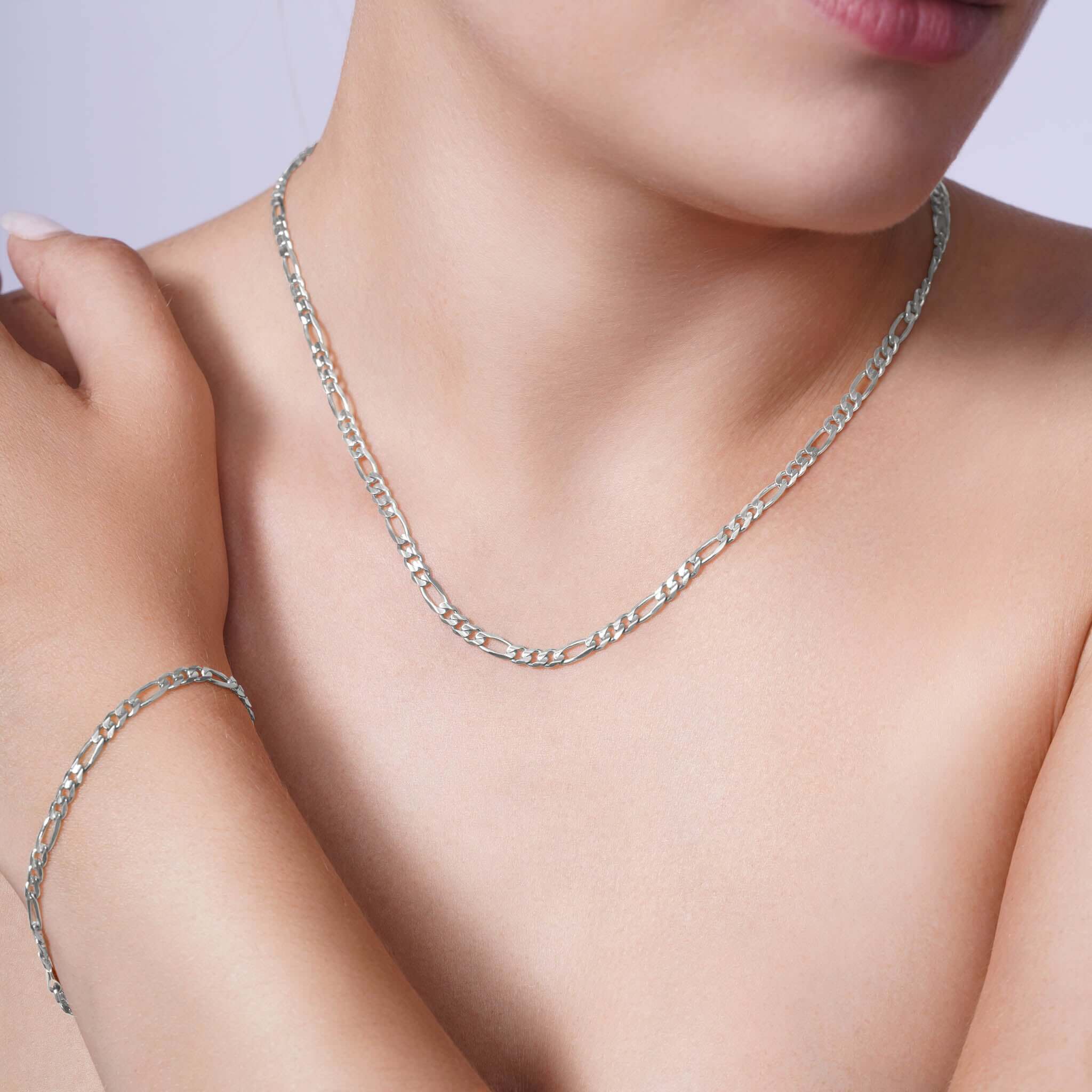 Elegant woman wearing a Figaro Gold Chain and bracelet, showcasing classic style and sophistication in 14k white gold.
