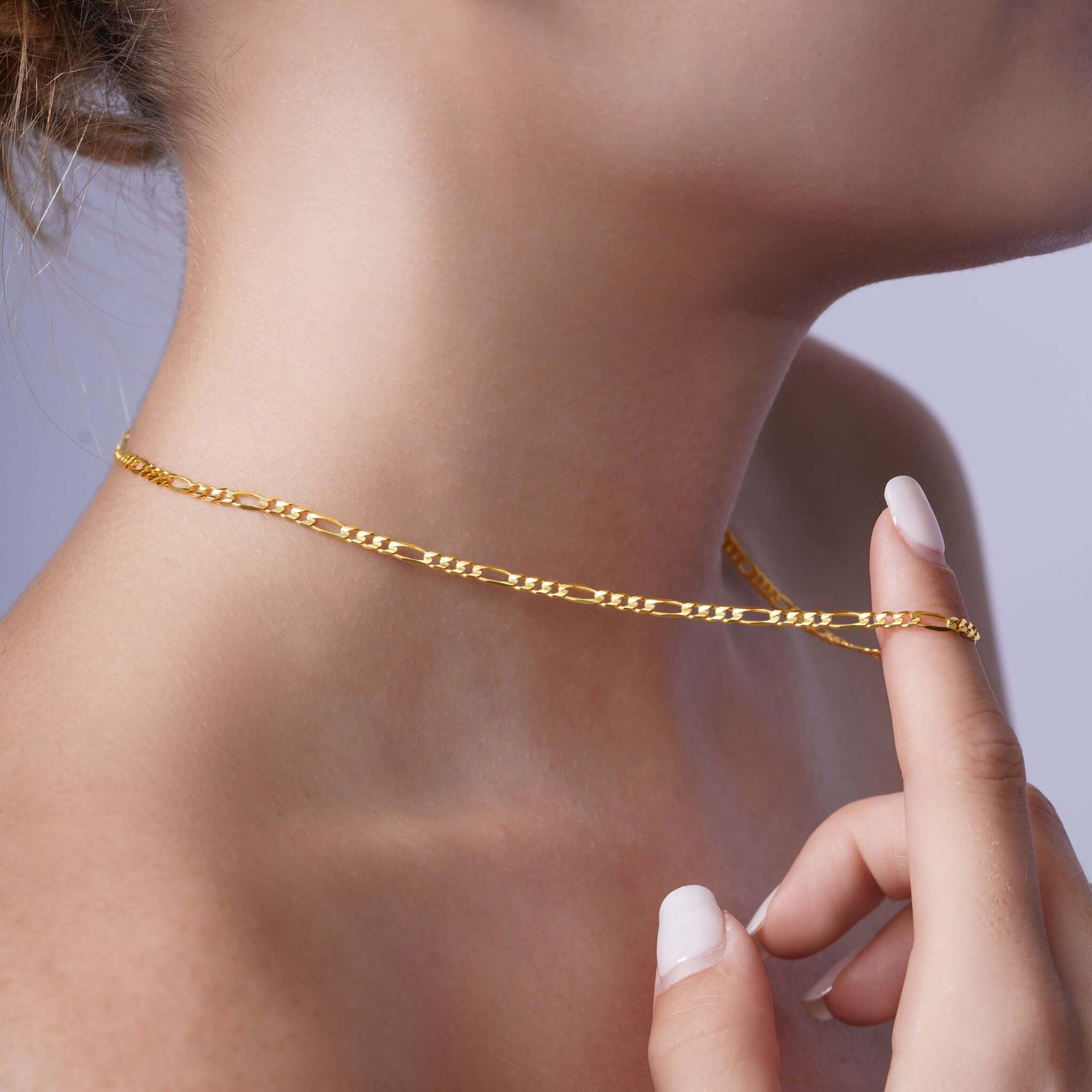 Figaro Gold Chain elegantly draped on a woman's neck, showcasing its distinctive design in 14k yellow gold.