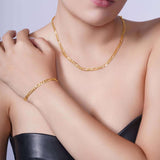 Elegant woman wearing a Figaro Gold Chain necklace and bracelet, showcasing timeless jewelry perfection.
