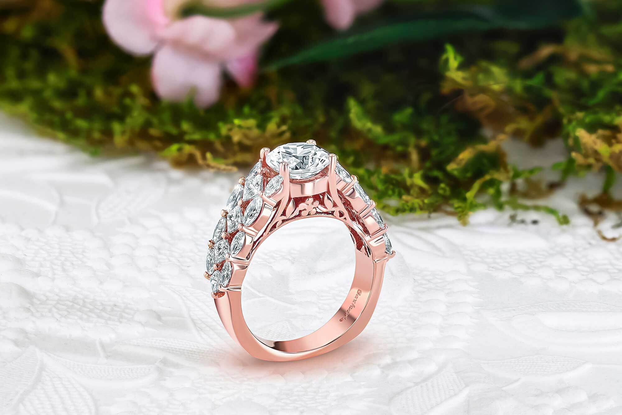 Rose gold ring with diamonds on a textured white surface with greenery in the background