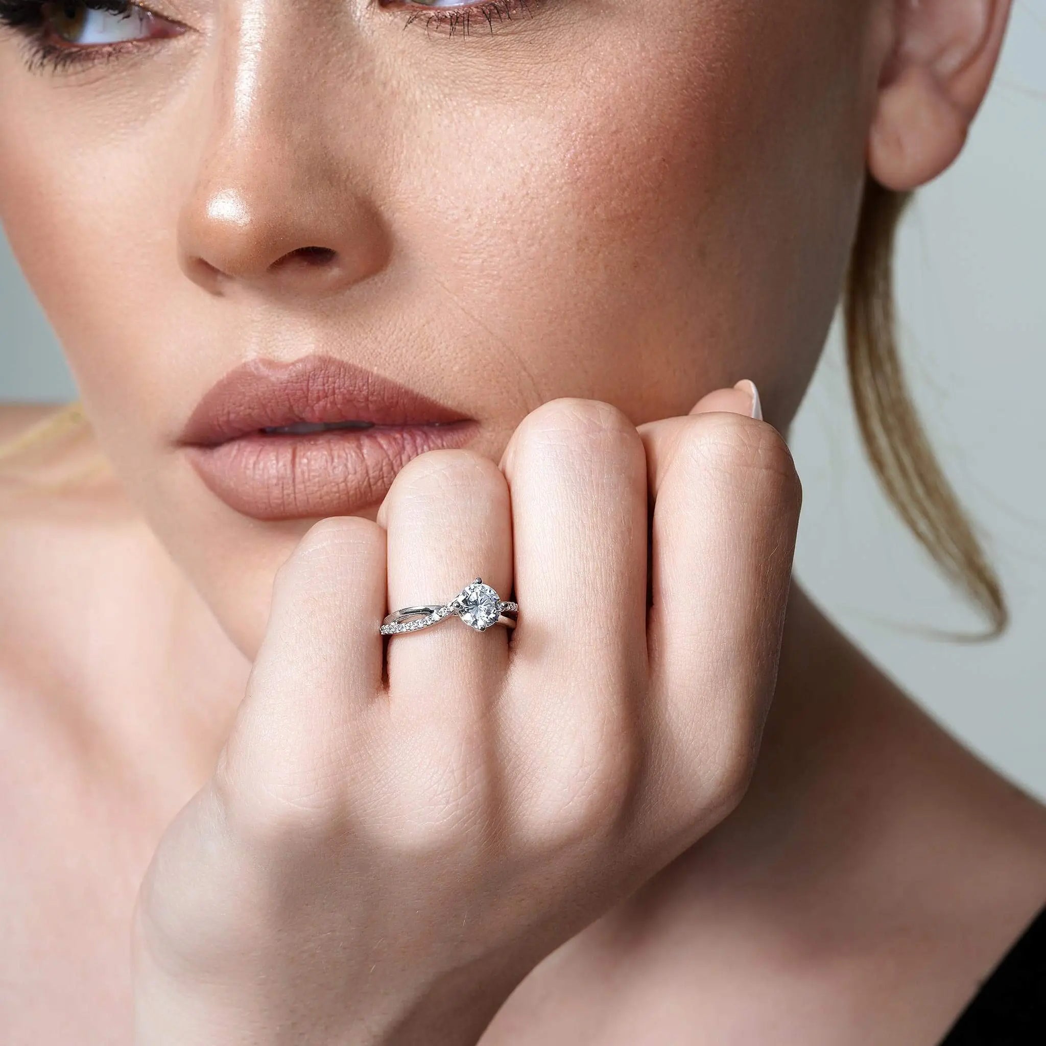 Close-up of a woman showcasing a diamond engagement ring on her hand, highlighting its elegant design and sparkle.