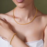 A model showcasing an 18K Gold Vermeil Franco Chain and bracelet on a neutral background.