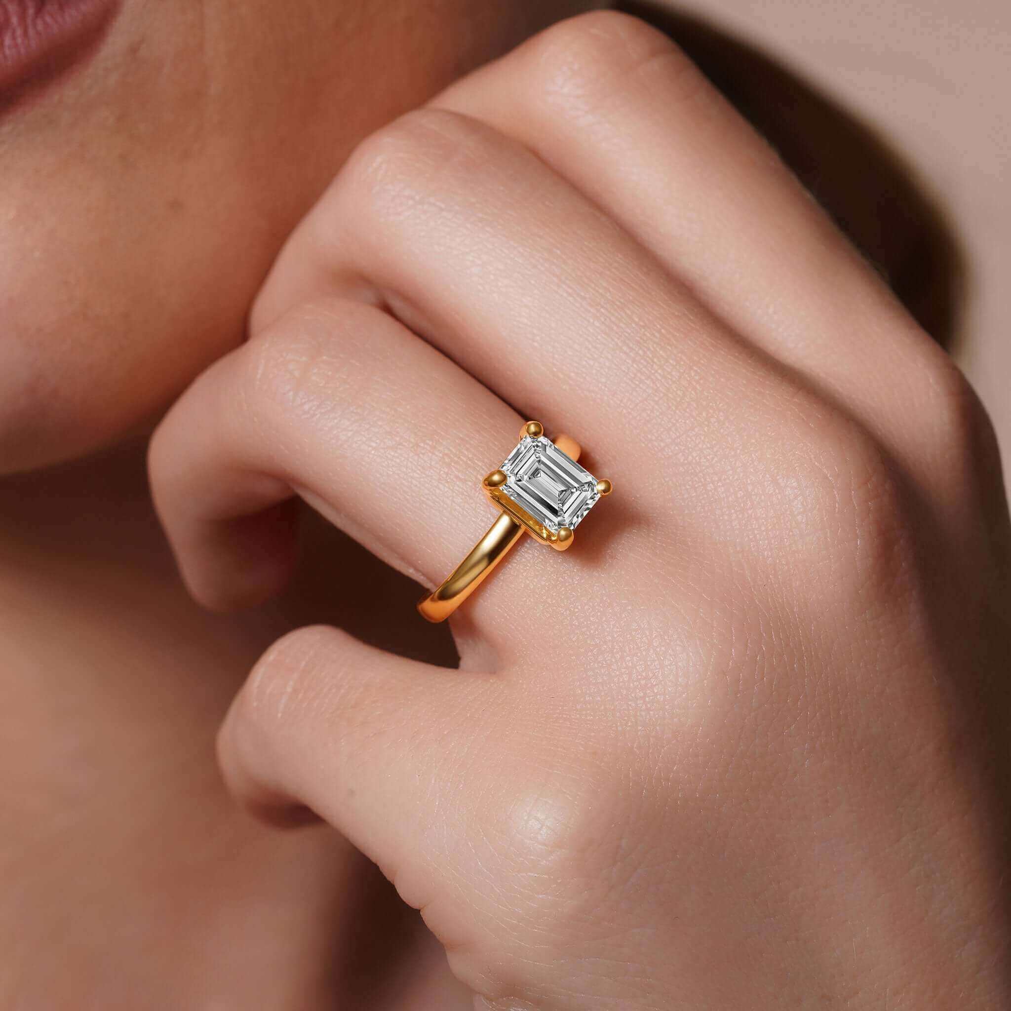 Emerald Cut Lab Grown Diamond Solitaire Engagement Ring on hand, showcasing a 2.00ct center stone and gold band.