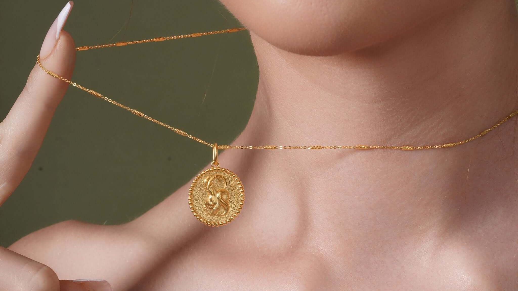 Model wearing a Zodiac Necklace showcasing a gold medallion with zodiac symbol on a delicate chain.