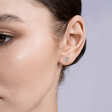 Close-up of an ear wearing a silver earth element alchemy stud earring against a neutral background