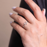 Hand wearing a silver triangle ring with a blurred background