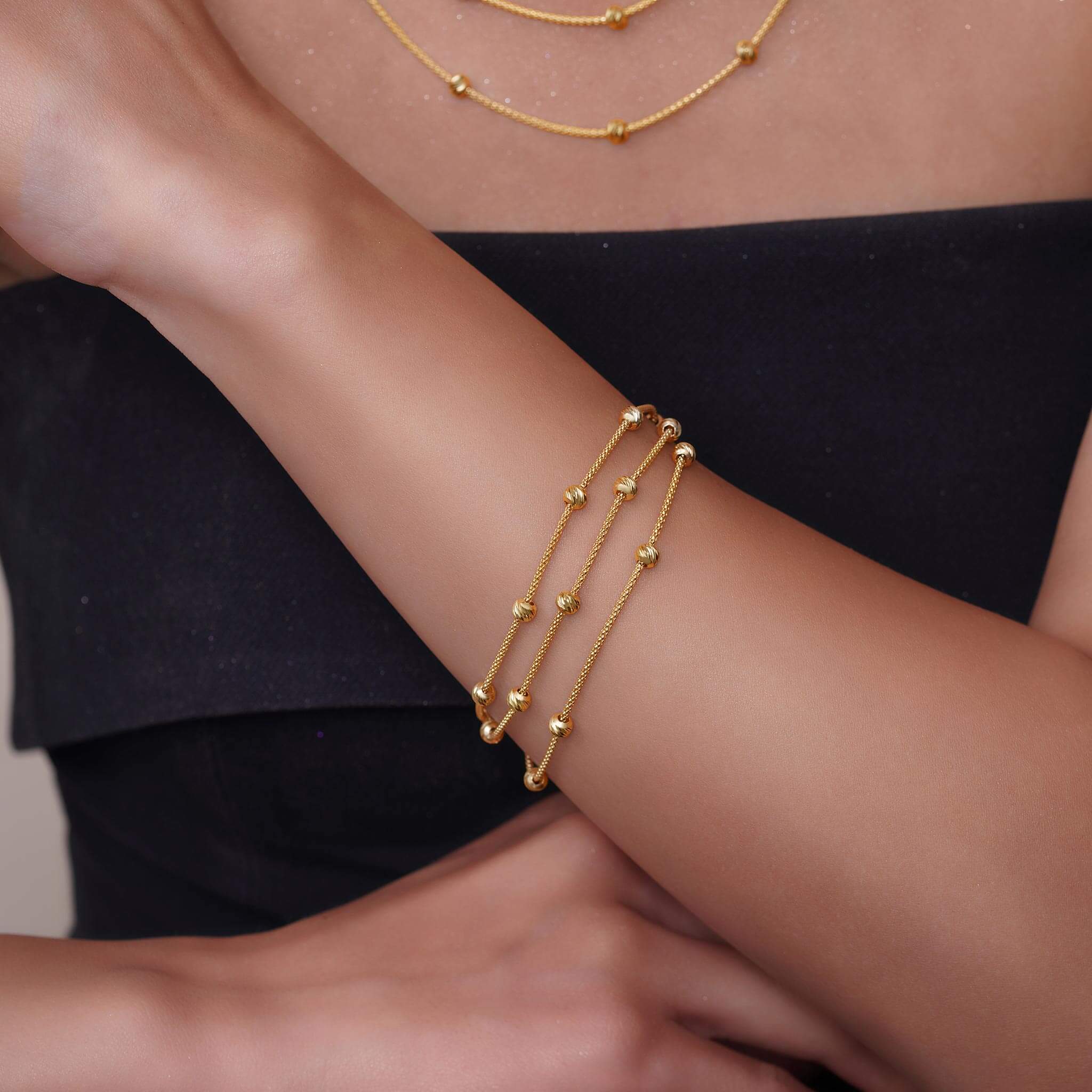 Close up of a gold bracelet featuring triple strands with evenly distrubuted stationary beads