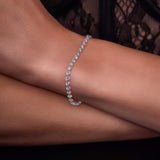 Diamond linked tennis bracelet on a person's wrist with a dark lace background
