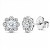 A pair of silver stud earrings with a halo design featuring a round clear center stone surrounded by smaller halo stones, shown on a plain white background. One earring is shown from the front, and the other is angled to show the post and backing with '925' sterling silver stamped on it.