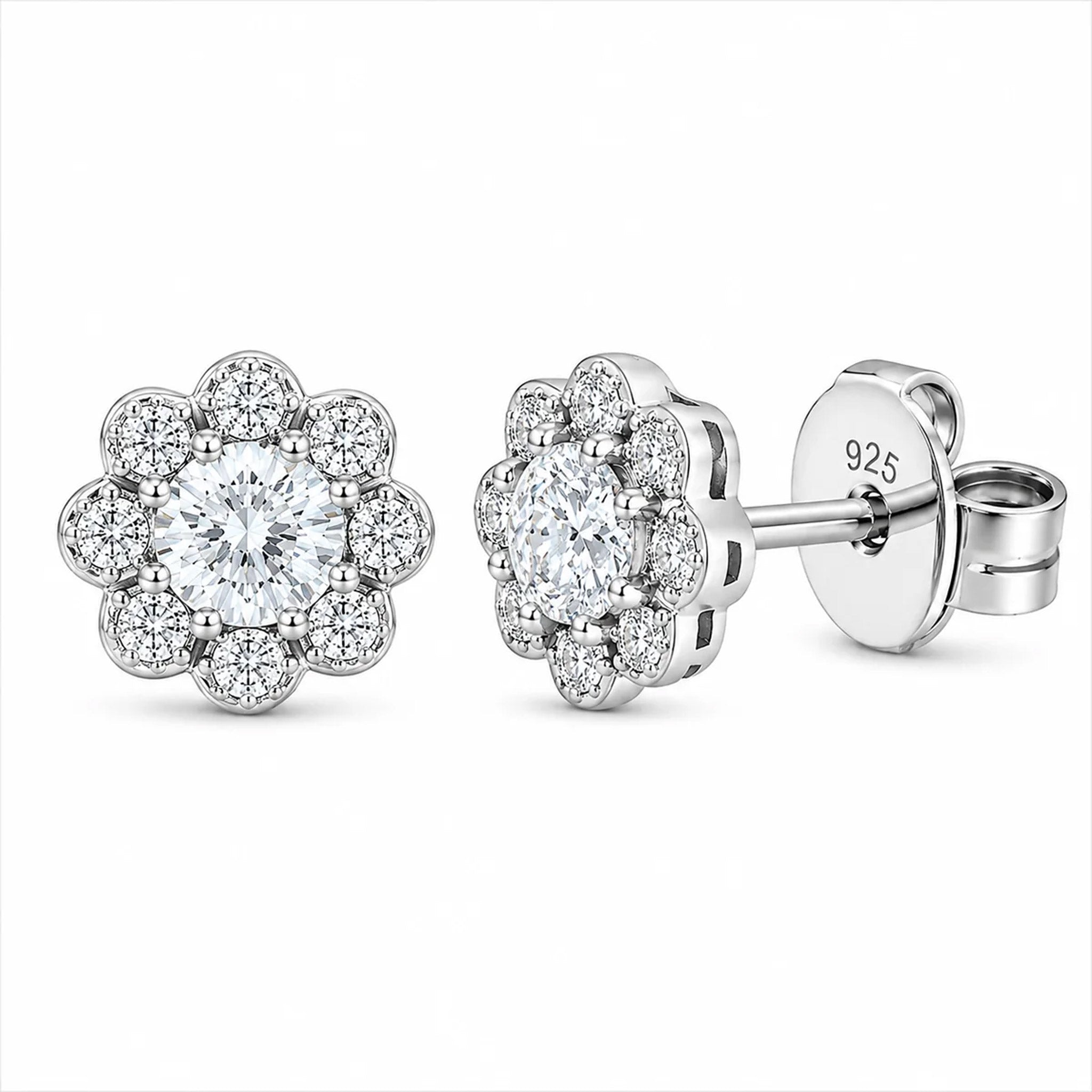 A pair of silver stud earrings with a halo design featuring a round clear center stone surrounded by smaller halo stones, shown on a plain white background. One earring is shown from the front, and the other is angled to show the post and backing with '925' sterling silver stamped on it.