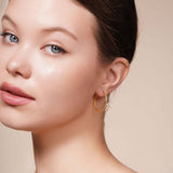 Close-up of a model wearing Gold Endless Hoop Earrings, showcasing their elegant design and gold finish.