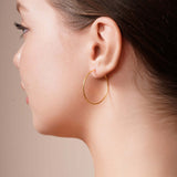 Model wearing Gold Endless Hoop Earrings highlighting timeless elegance and durability.
