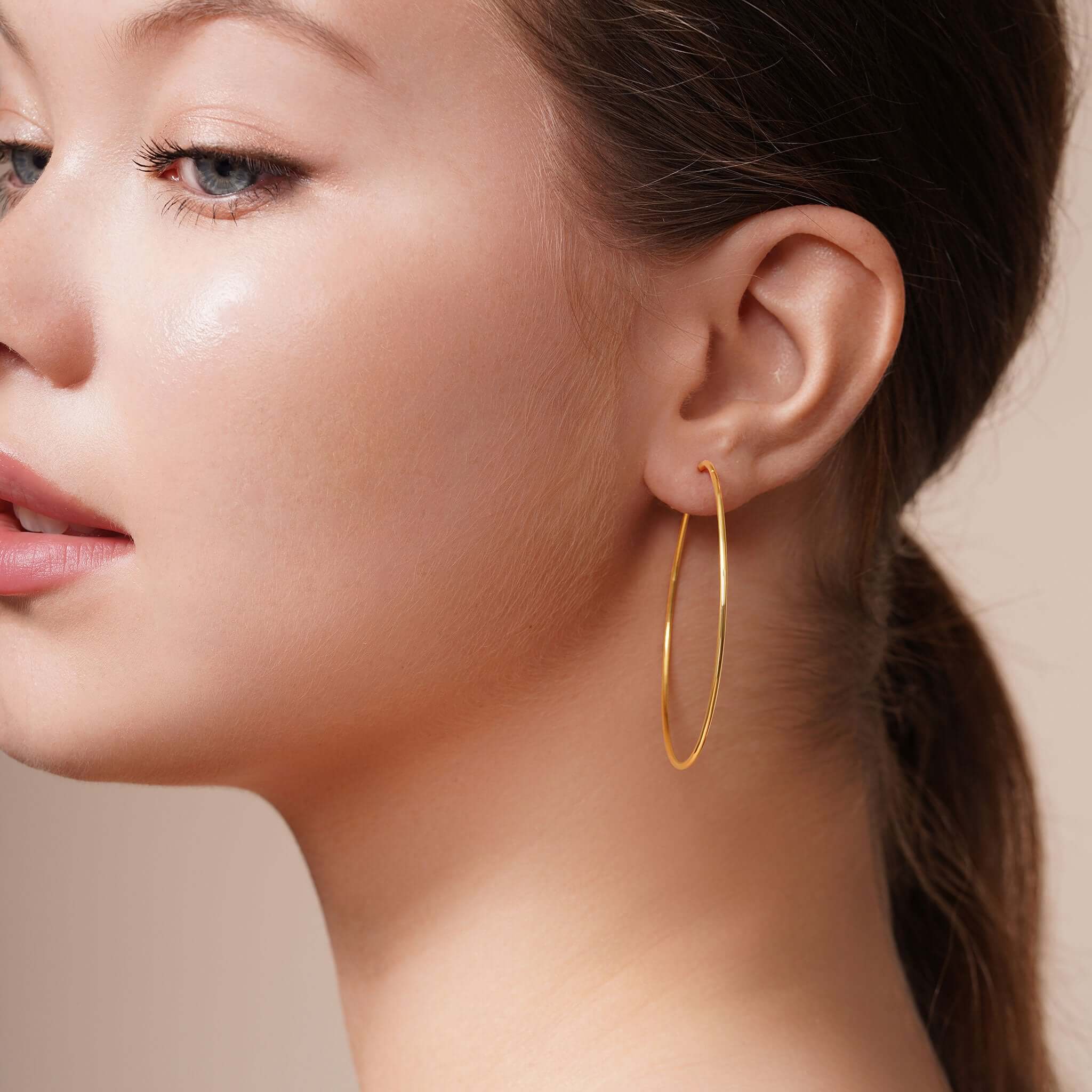 Profile view of a model wearing Gold Endless Hoop Earrings, showcasing their elegant design and shine.