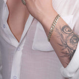 Men's solid gold curb bracelet worn on wrist with tattoo, showcasing elegance and style in white gold.