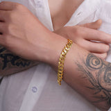 Men's solid gold curb bracelet on a wrist, showcasing luxurious 14K gold craftsmanship and a classic design.
