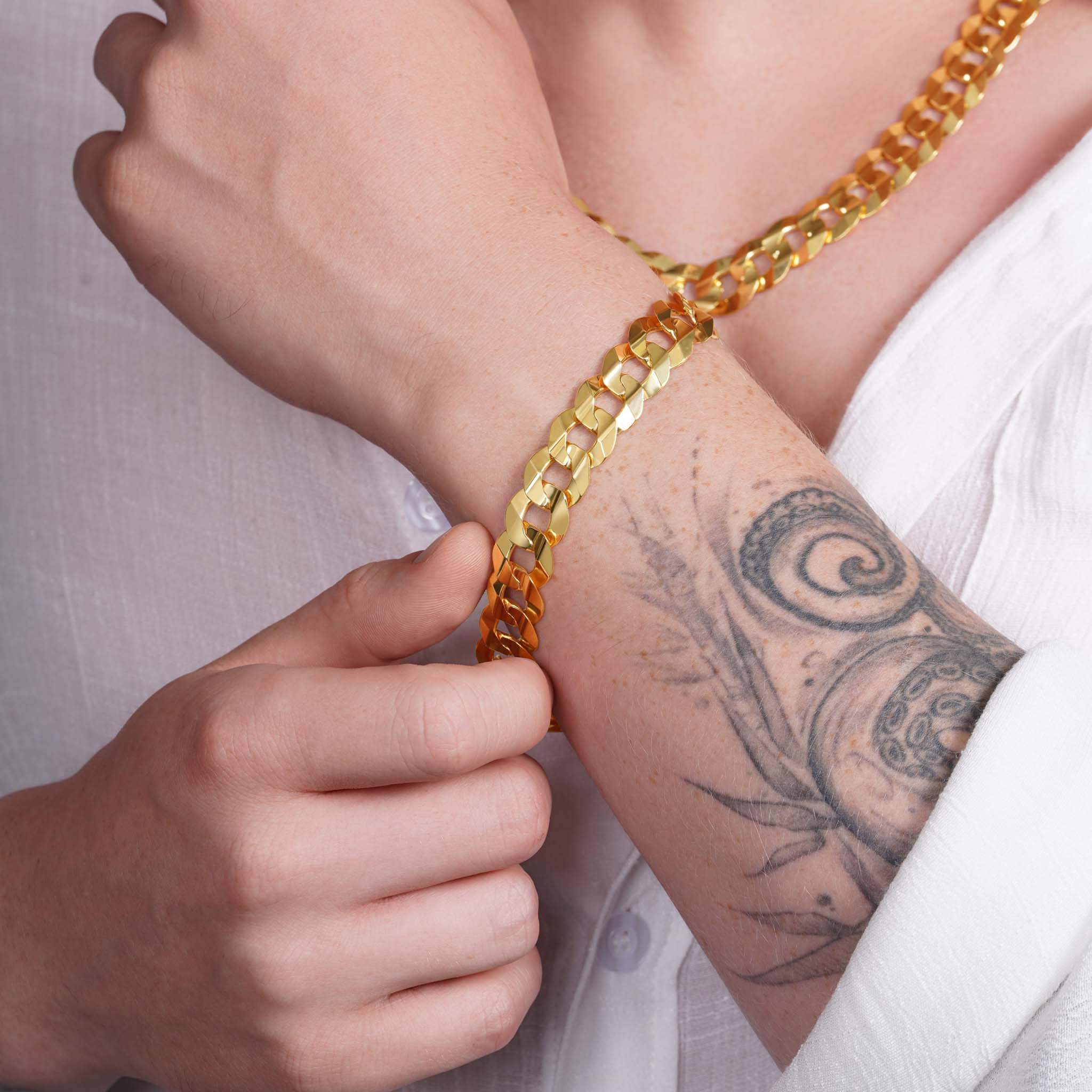 Man wearing a 14K solid gold curb bracelet, showcasing its elegant design and craftsmanship.