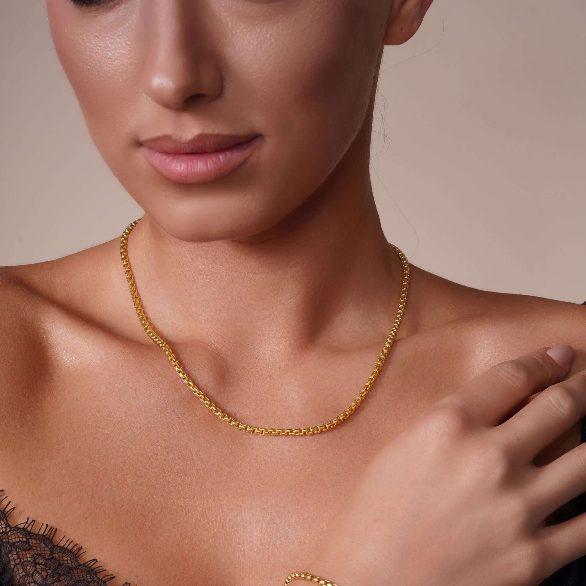 Close-up of a woman wearing a gold Round Box Chain necklace, showcasing elegance and style.