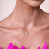 Close-up of a model wearing a Round Moissanite Silver Pendant Necklace with a vibrant pink floral background.