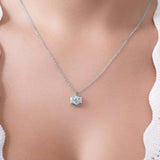 Silver necklace with a hexagonal pendant on a person wearing a white top.