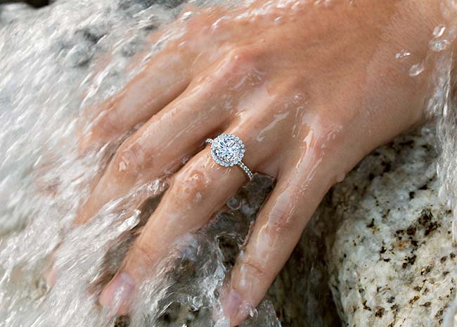 Hand with diamond ring on rock with water flowing over it